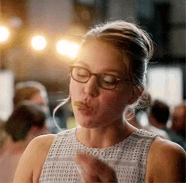 a woman wearing glasses is making a funny face while eating something .