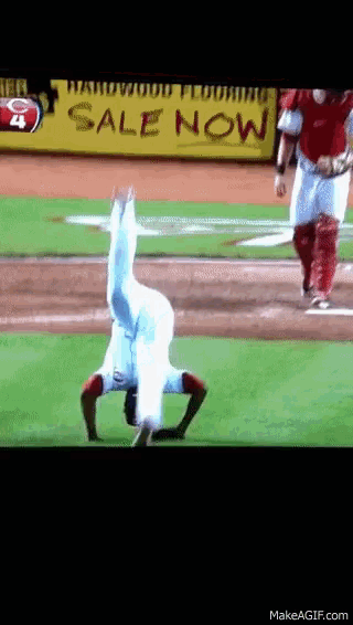 a baseball player doing a handstand in front of a sale now sign
