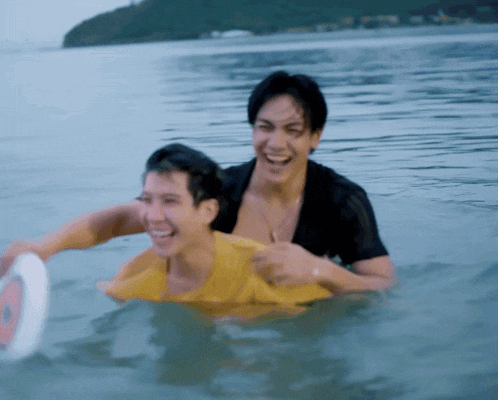 a man in a yellow shirt is being pulled by another man in the water