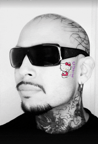 a man with a hello kitty tattoo on his face has sunglasses on