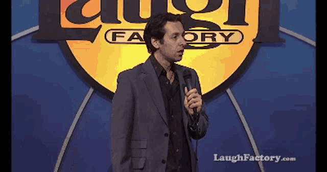 a man is giving a speech in front of a sign that says laugh factory