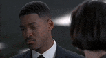 a man in a suit and tie is looking at a woman in a black shirt .