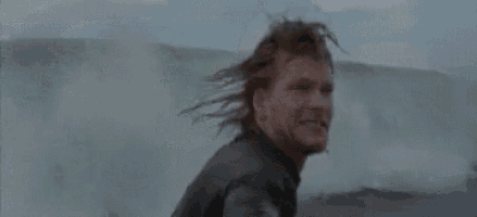 a man in a wet suit is standing in the water and smiling .