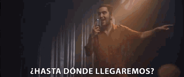 a man is singing into a microphone in a dark room with the words hasta donde llegaremos written below him .