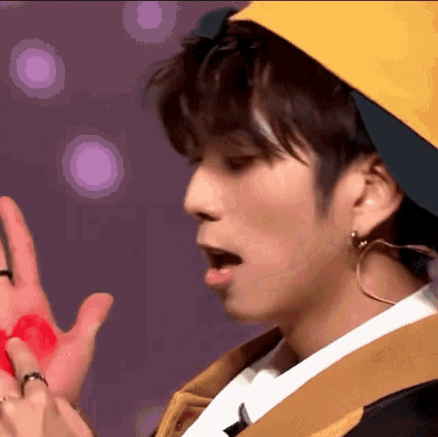 a close up of a man wearing a yellow hat and earrings