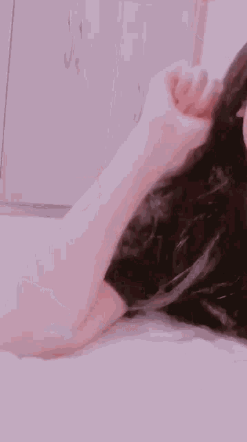 a woman is laying on a bed with her eyes closed and her hand up .