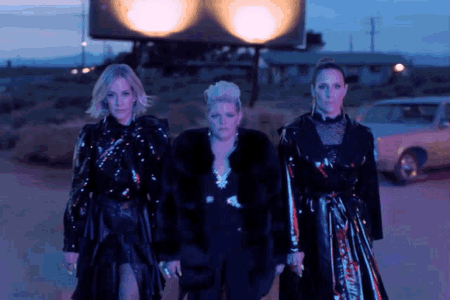 three women are standing in front of a billboard