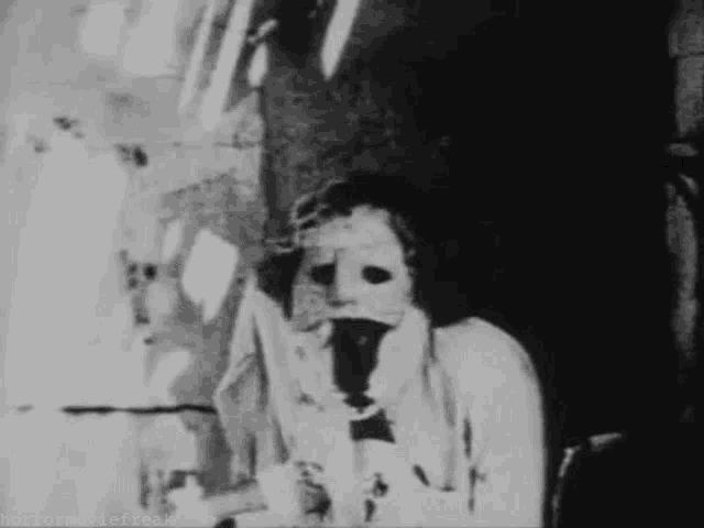 a black and white photo of a man wearing a mask and suspenders .