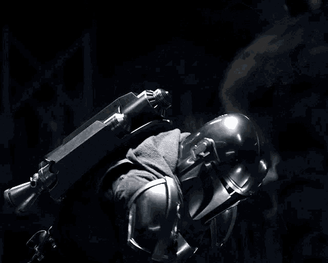 a man in a helmet is standing in the dark with a gun on his back .