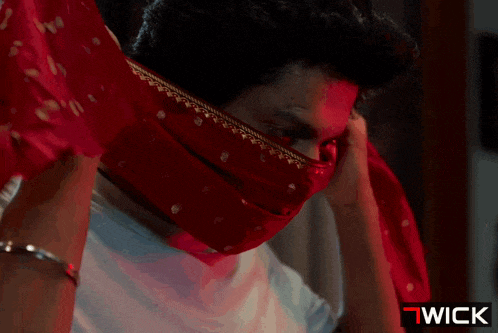 a man is covering his face with a red scarf and the word wick is on the bottom right