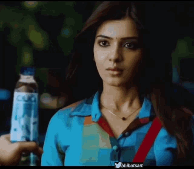 a woman in a blue shirt is holding a bottle of water