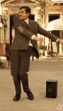 a man in a suit is dancing on the street in front of a restaurant