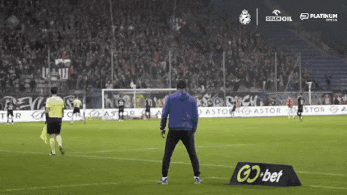 a man stands on a soccer field next to a sign that says go bet