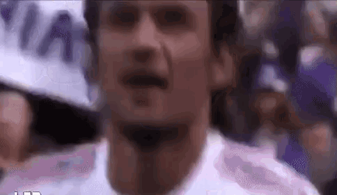 a close up of a man 's face in a white shirt with a crowd in the background .