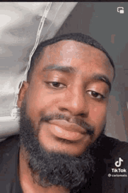 a man with a beard is making a funny face and smiling .