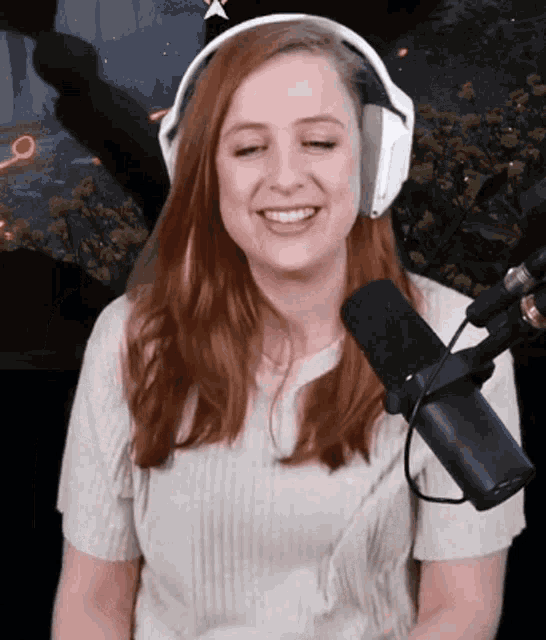 a woman wearing headphones stands in front of a microphone