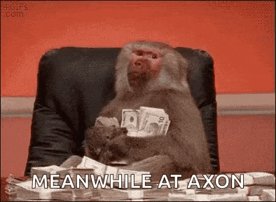 a monkey is sitting in a chair holding a stack of money and says meanwhile at axon .