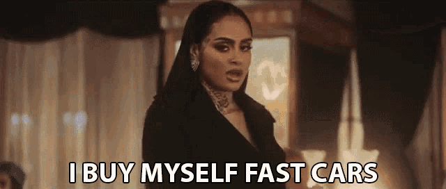a woman is standing in a room with the words `` i buy myself fast cars '' written on the screen .