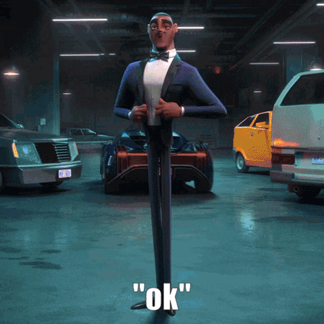 a man in a tuxedo is standing in a garage with cars and says " ok " on the bottom