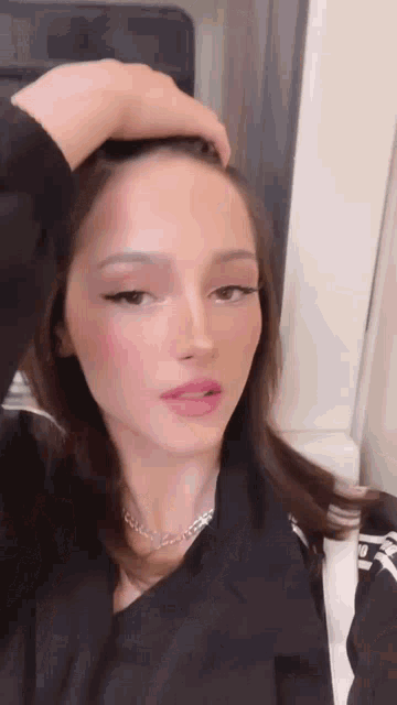 a close up of a woman 's face with her hand on her head