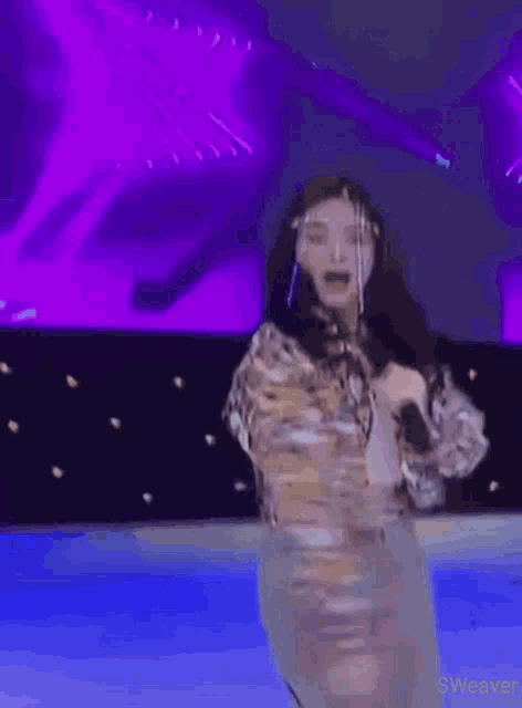 a woman is singing into a microphone on a stage .