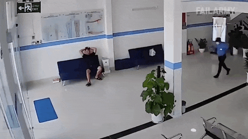 a man sits on a couch in a hallway with an exit sign on the wall