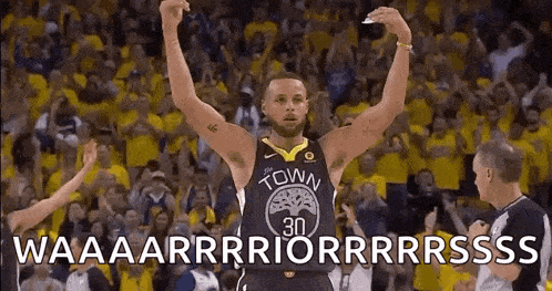 a basketball player is raising his arms in the air while standing in front of a crowd of people .