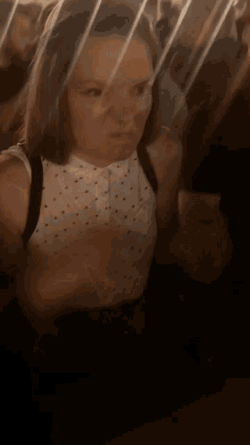 a woman in a polka dot shirt is sitting in a crowded room