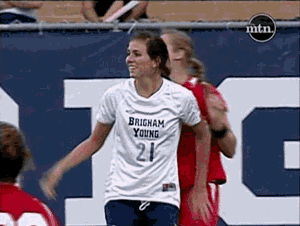 a woman wearing a brigham young jersey is being hugged by another woman