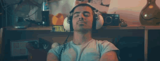 a man wearing headphones is listening to music with his eyes closed in a room .