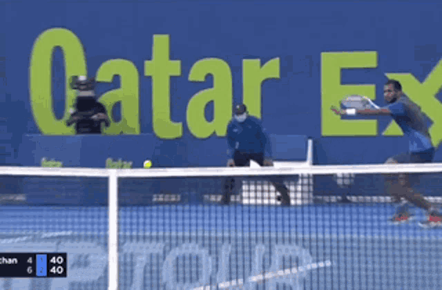 a man is playing tennis in front of a sign that says catar