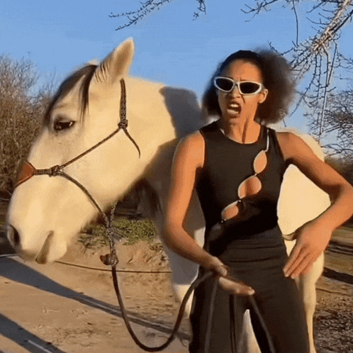 a woman standing next to a white horse wearing sunglasses