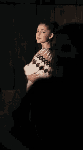 a woman in a plaid sweater is standing in a dark room with her eyes closed
