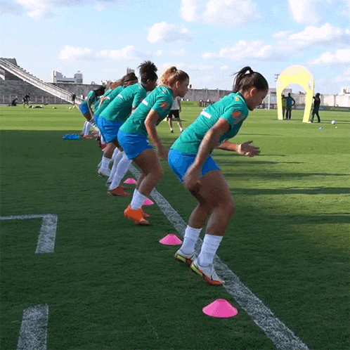 a group of female soccer players wearing green and blue uniforms