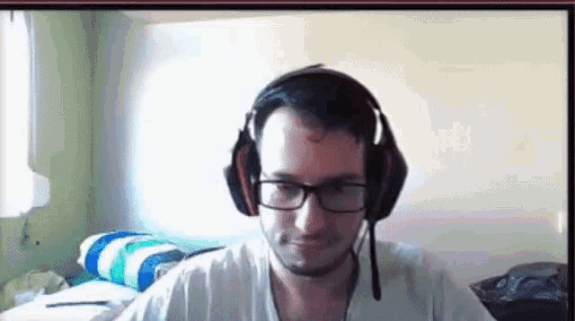 a man wearing headphones and glasses is sitting in front of a computer .