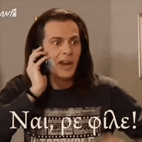 a man with long hair is talking on a cell phone while wearing a t-shirt that says ant