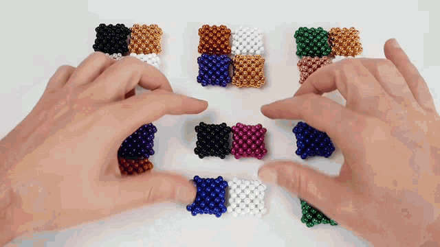 a person is playing with a bunch of different colored magnet beads