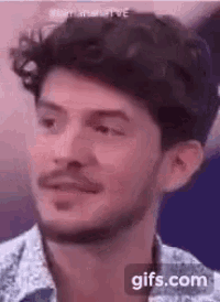 a close up of a man 's face with a beard and a floral shirt .