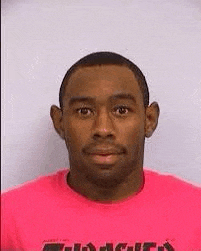 a man wearing a pink shirt is looking at the camera .