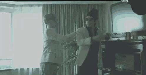two people are dancing in a living room in front of a flat screen tv .
