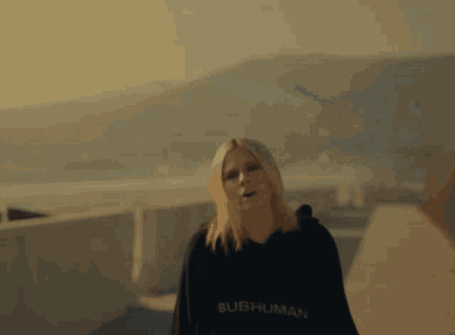 a woman wearing a black hoodie that says subhuman on the front