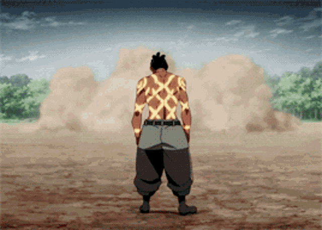 a man with a tattoo on his back is standing in the dirt
