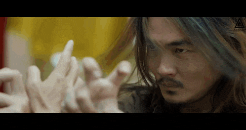 a man with long hair and a beard is reaching out towards a group of people .