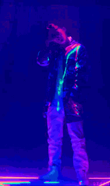 a man in a glow in the dark outfit is standing in front of a purple light