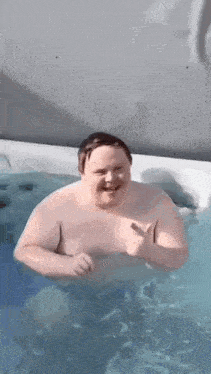 a shirtless man is swimming in a hot tub .