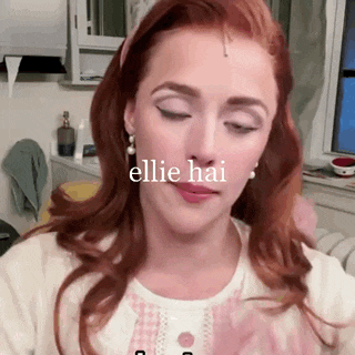 a woman with red hair is wearing a headband and earrings and making a funny face .