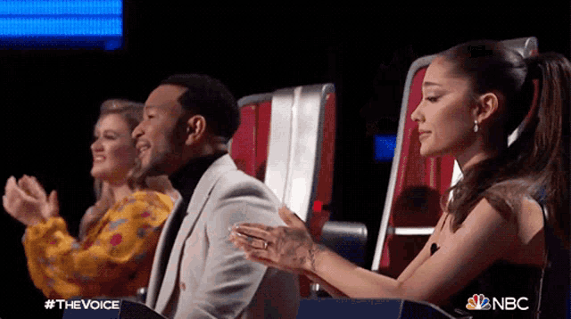 john legend and ariana grande are applauding during a performance on the voice