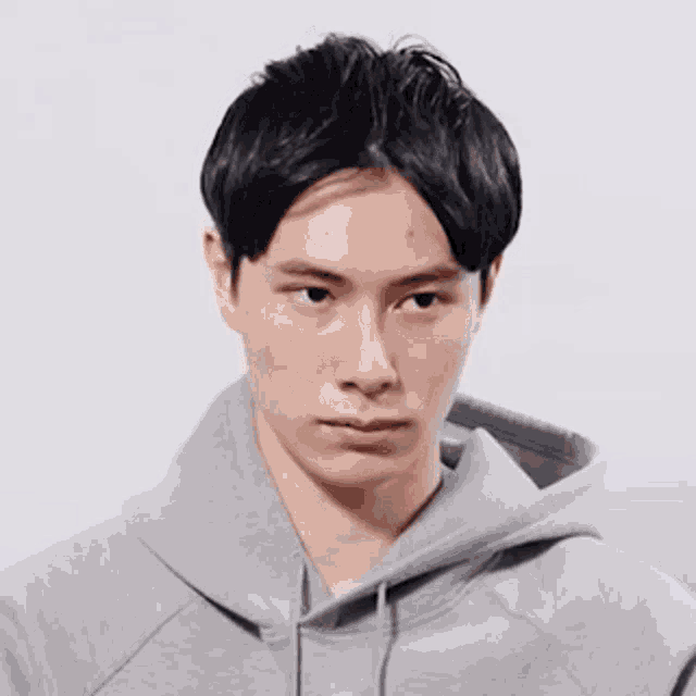 a young man wearing a grey hoodie is smiling for the camera