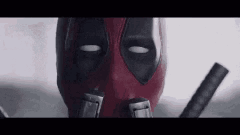a close up of deadpool 's face with a sword in his hand .