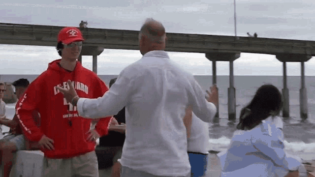 a man in a red cleveland lifeguard sweatshirt is dancing with another man